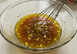 Whisking olive oil, red wine vinegar, lemon, Dijon, oregano for Greek dressing