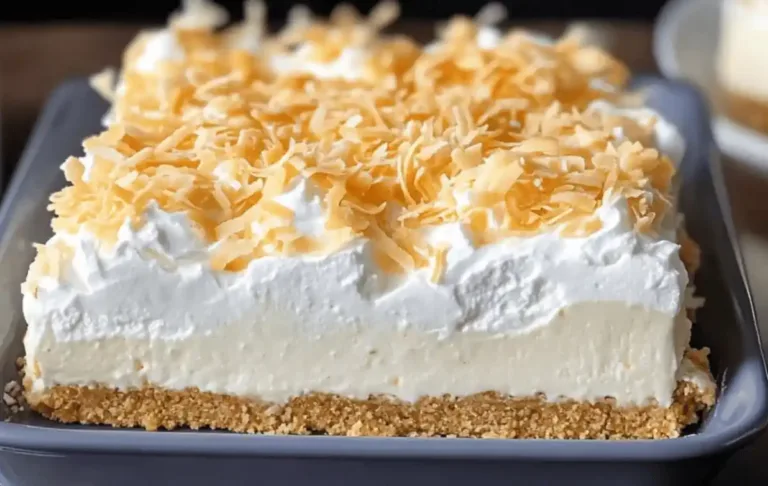Layered Coconut Cream Lush dessert with graham cracker crust, coconut cheesecake, pudding, whipped cream, and toasted coconut topping in a glass dish.