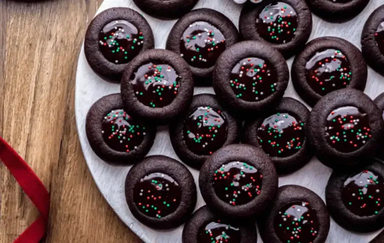 Close-up of rich chocolate thumbprint cookies filled with glossy melted chocolate, arranged neatly on a baking tray, showcasing their chewy texture and decadent center.