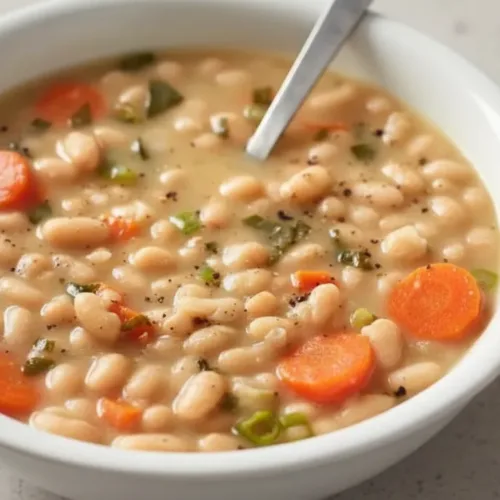 Bowl of Greek white bean soup with garlic and lemon garnish